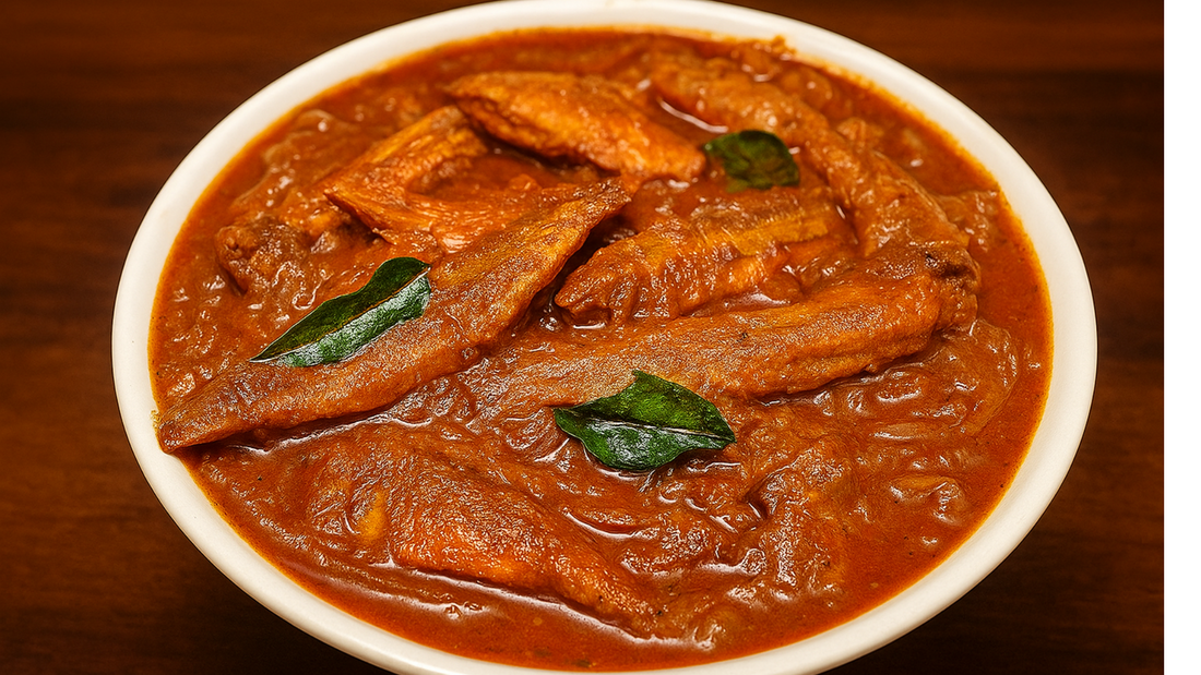 Close-up of spicy Dry Queen Fish Curry made with rich red masala, crispy dry fish, and garnished with fresh curry leaves, served in a white bowl on a wooden background